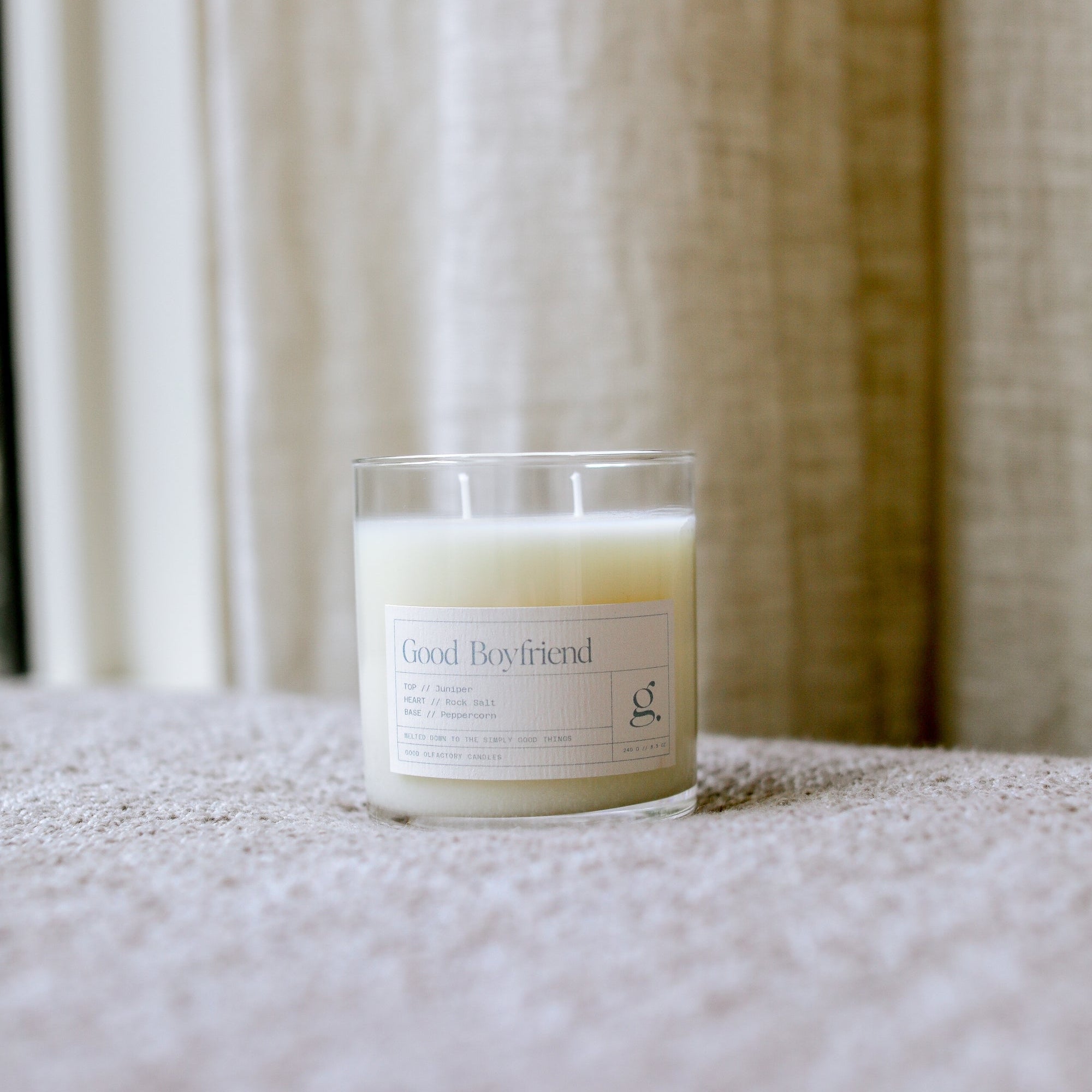 Candle labeled 'Good Boyfriend' on a textured surface with a neutral background